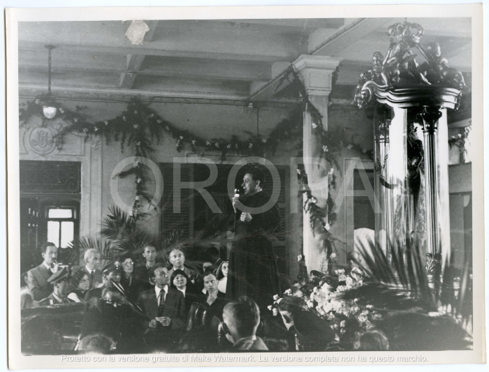 [94523] Un parroco a fianco alla statua parla al microfono rivolto verso i fedeli.