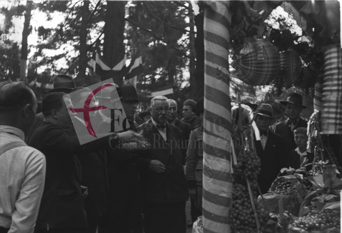 Biella, anni ‘30. Festa dell’Uva. Il podestà di Biella Giuseppe Serralunga (a sinistra dell’uomo con il fez) ammira l’uva esposta in uno dei chioschi che affollavano i Giardini Zumaglini (Archivio Cesare Valerio - Proprietà Fondazione Cassa di Risparmio di Biella)