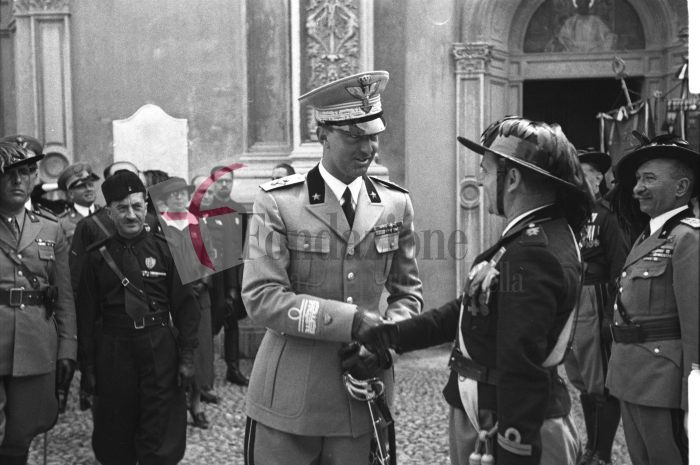 Biella, 17 giugno 1936. Il principe Umberto di Savoia davanti alla basilica di San Sebastiano per le celebrazioni del centenario della fondazione del Corpo dei Bersaglieri. Accanto a lui, a sinistra, il gerarca biellese Baldassarre Trabucco. Foto C. Valerio (proprietà Fondazione Cassa di Risparmio di Biella)