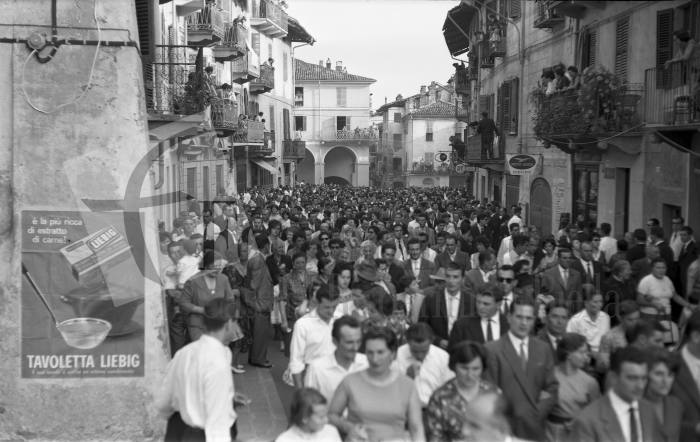 Masserano, 24 settembre 1961. Festa dell’Uva. Via Roma invasa da una folla festante. Sul muro in primo piano spicca la pubblicità della tavoletta per brodo Liebig (Archivio Lino Cremon - Proprietà Fondazione Cassa di Risparmio di Biella)