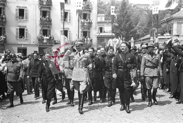 Biella, 17 giugno 1936. Il principe Umberto di Savoia in piazza Quintino Sella (l'attuale piazza Martiri della Libertà) per l’inaugurazione della Prima Mostra Laniera. Accanto a lui il gerarca Baldassarre Trabucco (a sinistra) e il podestà di Biella Giuseppe Serralunga. Dietro si riconoscono Paolo Zerbino e Zaverio Luigi Bracco. Foto C. Valerio (proprietà Fondazione Cassa di Risparmio di Biella)